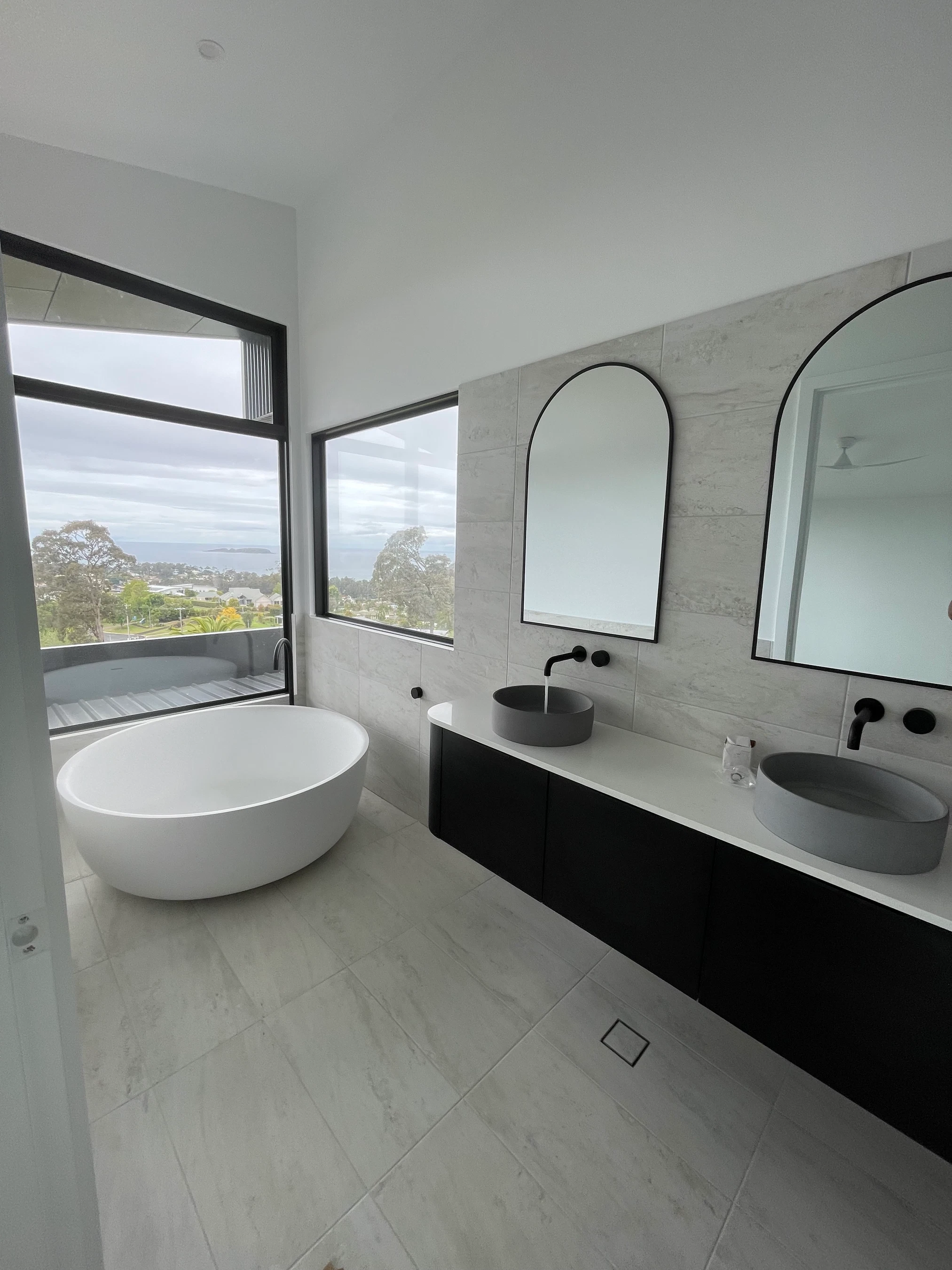 Modern ensuite bathroom with freestanding bath and coastal views