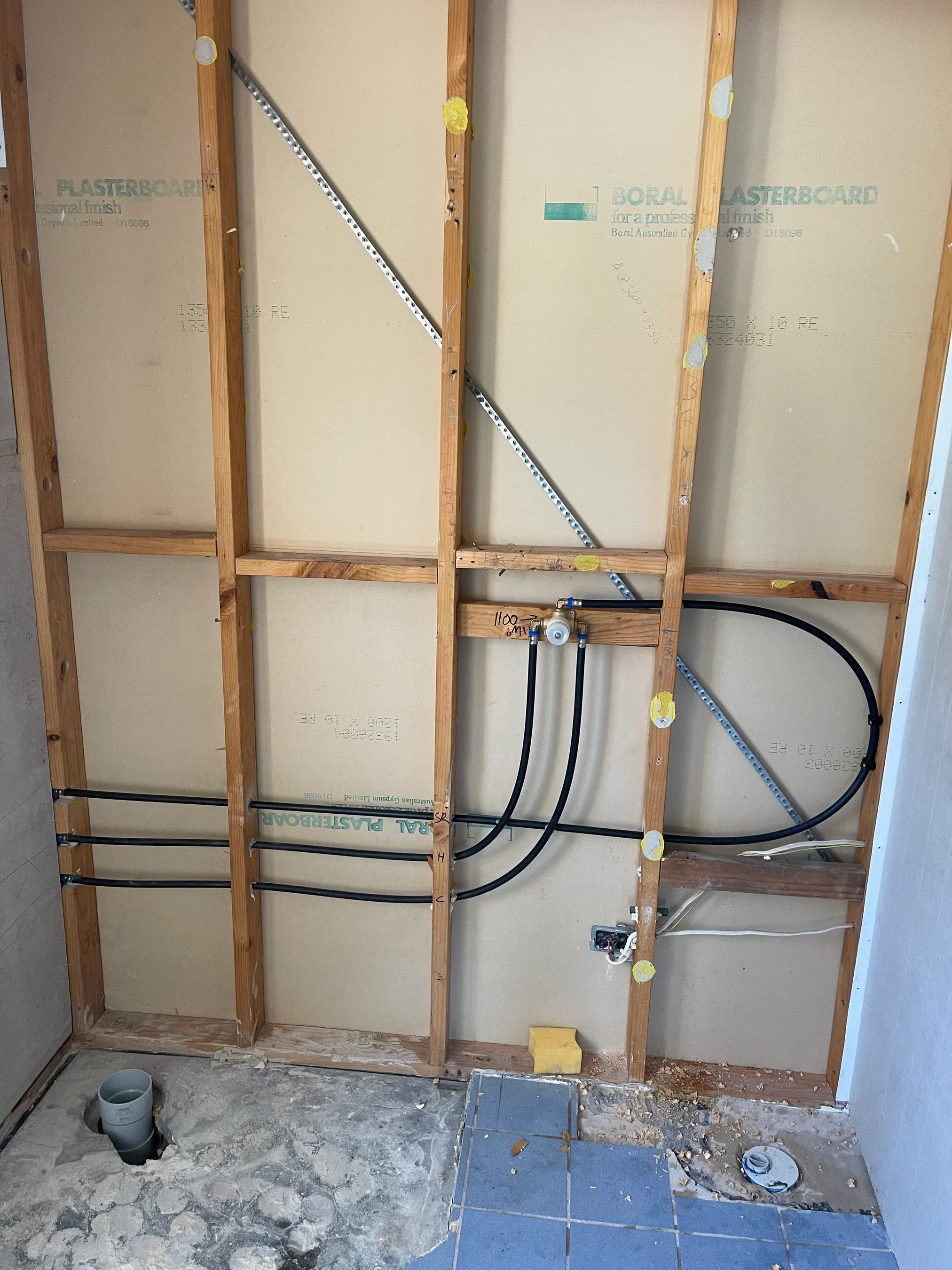 Shower mixer valve and black pipe rough-in behind timber studs